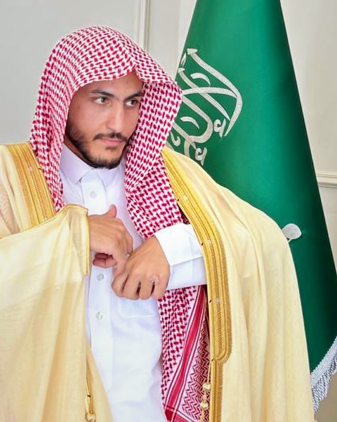 المحامي سالم خلف الشمري بالبشت، وبجانبه علم المملكة العربية السعودية